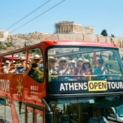 Κόκκινο διώροφο τουριστικό λεωφορείο Hop-on Hop-off μπροστά από την Ακρόπολη στην Αθήνα.
