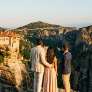 Ζευγάρι απολαμβάνει μια ιδιωτική ξενάγηση στα Μετέωρα κατά το ηλιοβασίλεμα, με θέα τα μοναστήρια.