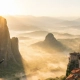 Ζευγάρι απολαμβάνει την ανατολή στα Μετέωρα σε ιδιωτική ξενάγηση, με θέα τα μοναστήρια και την ομίχλη.